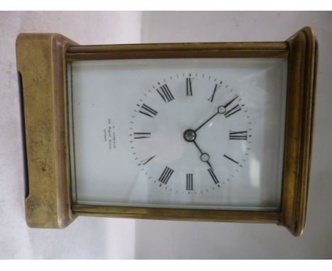 An early 20thC lacquered brass cased carriage clock with bevelled glass panels and a folding top handle, on a bracket plinth;