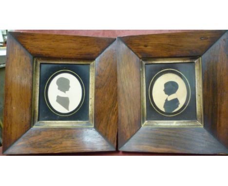 A pair of late Regency profile portrait silhouettes, respectively featuring a boy and a girl, in glazed, wide, mitred rosewoo