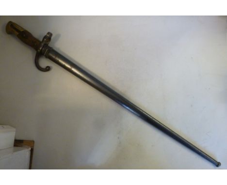 A late 19thC French sword type bayonet with a brass mounted and rivetted, two part handgrip, the blade inscribed 'Mre d'Armes