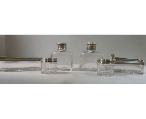 A William IV six piece set of chamfered, facet and star cut glass toiletry receptacles with silver caps and covers with conce
