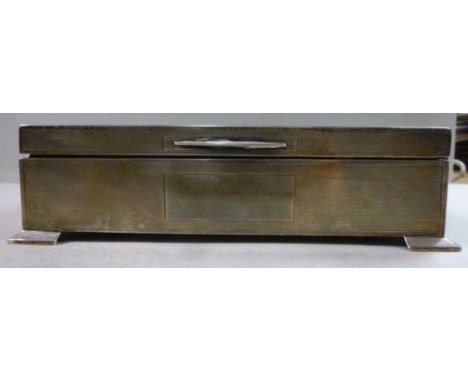 A silver cigarette box with engine turned decoration, straight sides and a hinged lid, on bracket feet, enclosing a cedar lin