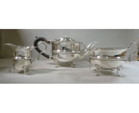 An Edwardian three piece silver tea set of cauldron design with cut, flared rims  comprising a teapot with a wooden handle, s