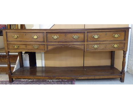 A late 18thC honey coloured oak and crossbanded mahogany dresser base, the planked top having a thumb moulded edge, over thre