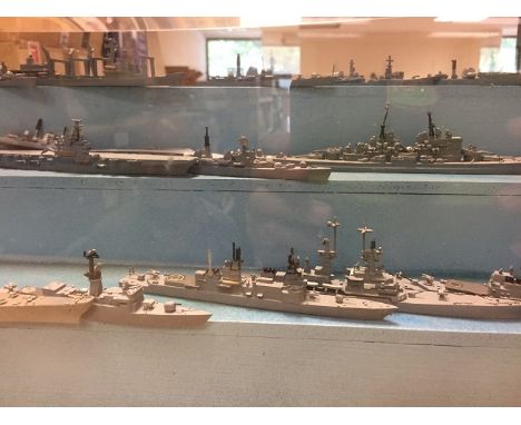 A large collection of 1:1200 scale or similar metal British Naval waterline Vessels,  presented on a three tier shelf display