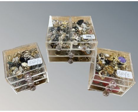 Three small nests of perspex drawers containing a collection of costume earrings, Art Deco buckles etc. (3)