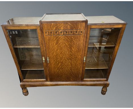 An oak Art Deco double door glazed bookcase fitted with central panel door on raised legs.