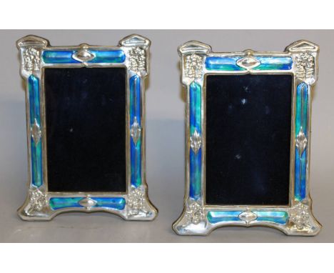 A PAIR OF ART NOUVEAU STYLE SILVER AND ENAMEL PHOTOGRAPH FRAMES. 8ins x 6ins.