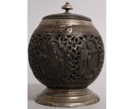 A 19TH CENTURY INDIAN CARVED NUT AND SILVER MOUNTED CADDY, carved and pierced with six ovals of figures, with silver mounts a
