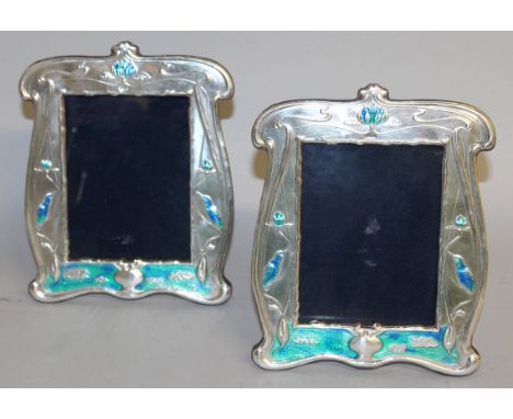 A PAIR OF ART NOUVEAU STYLE SILVER AND ENAMEL PHOTOGRAPH FRAMES. 8ins x 6ins.