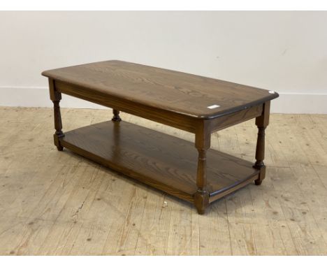 Ercol, a stained elm coffee table, the rectangular top over turned and block supports untied by an under tier. H44cm, W117cm,