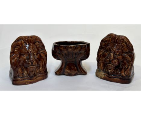 A group of three 19th century treacle-glazed pottery sash window rests: two modelled as lion masks, the third of shaped scrol