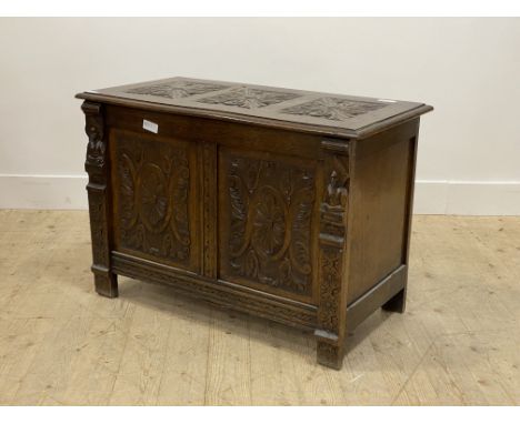 A 1930's oak coffer of 18th century design, floral carved hinged lid opening to a plain interior, over two panel carved front