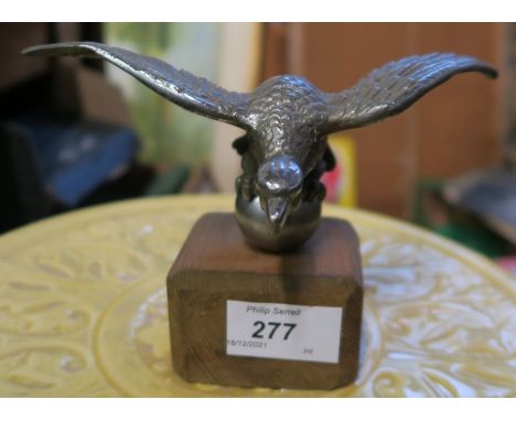 A desmo car mascot, of an eagle perched on a ball, possibly Alvis, on a wooden base, height 4.25ins