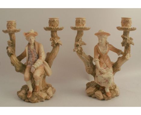 A pair of Royal Worcester blush ivory candelabra, formed as seated figures in the fork of branches on a tree, model numbers 1