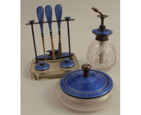 A silver, enamel and glass dressing table set, comprising a powder pot, an atomiser and a manicure set