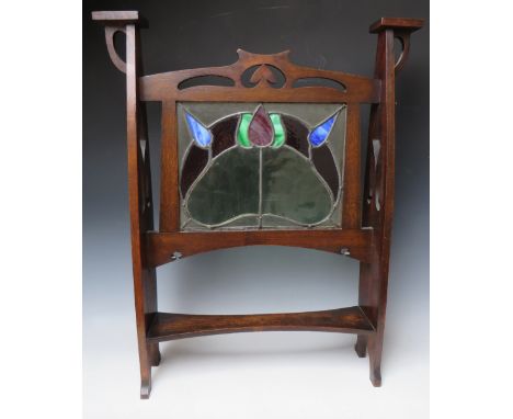 AN EARLY 20TH CENTURY OAK GLAZED ART NOUVEAU FIRE SCREEN, the glass panel with coloured and leaded stylised floral detail, th