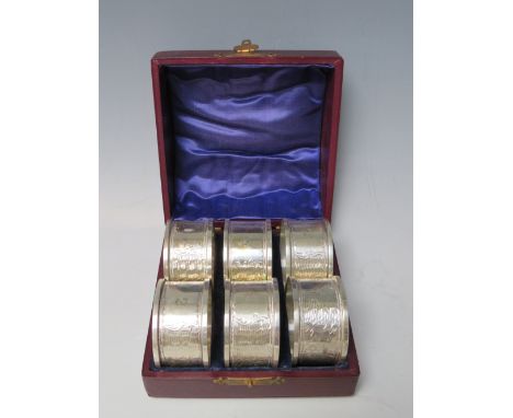 A CASED SET OF SIX EDWARDIAN HALLMARKED SILVER NAPKIN RINGS - BIRMINGHAM 1908, makers mark for J R, with engraved decoration 