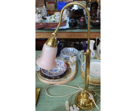 A brass adjustable electric lamp with pink glass shade