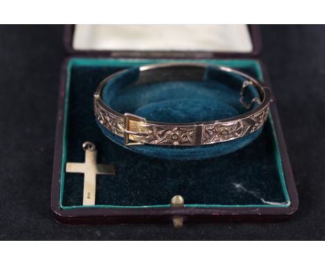 A 9ct gold bangle of belt and buckle design with foliate detail (dented) plus a small 9ct gold cross pendant