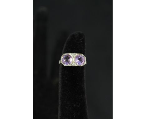 A white gold ring set with two large amethyst stones interspersed with diamonds, size J