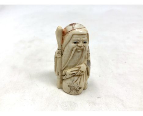 A Japanese carved bone netsuke - Village elder with a sack at his feet. 