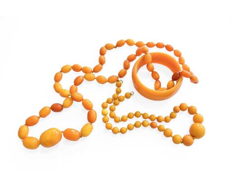 A Graduated Amber Bead Necklace, length 100cm (approximately); An Amber Type Necklace, length 47cm; and An Amber Type Bangle 