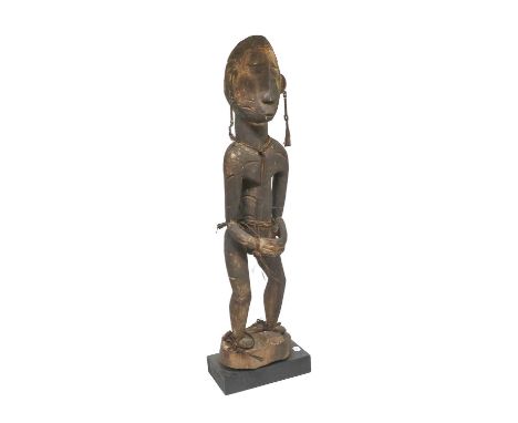 An Asmat Ancestor Figure, Papua Province, Indonesia, carved from dark stained soft wood, as a man standing, wearing seed and 