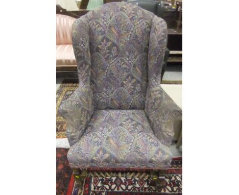 An early 20th Century oak framed wing back armchair with block and turned legs united by barley-twist stretchers and upholste