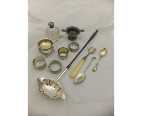 A box containing assorted silver wares to include a Georgian toddy ladle, various napkin rings, plated tea strainer, belt buc