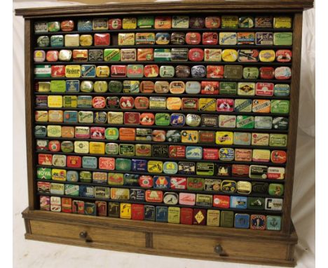 An oak sloping front display cabinet containing a collection of over 200 various gramophone needle tins including Columbia, E