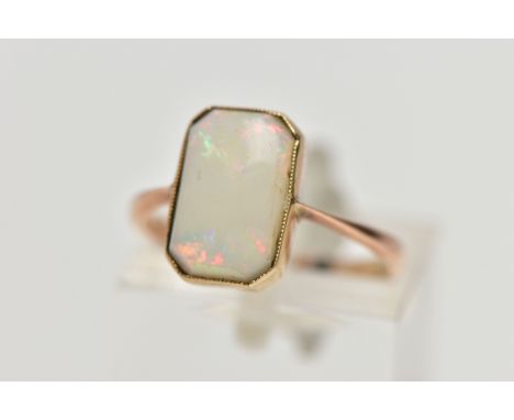 A YELLOW METAL OPAL RING, rectangular cut opal cabochon with cut off corners, milgrain collet mount, pinched shoulders leadin