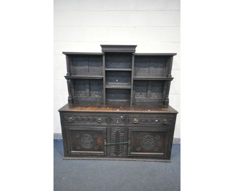 A 19TH CENTURY CARVED OAK DRESSER, the top with an arrangement of open shelves, over a base with three drawers and double pan