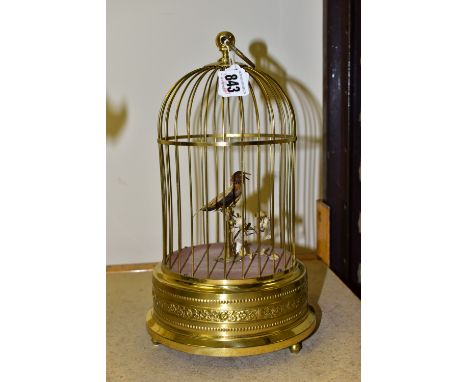 A REPRODUCTION AUTOMATON SINGING BIRD IN A BRASS CAGE, fitted with a hanging loop, embossed decoration to the stepped circula