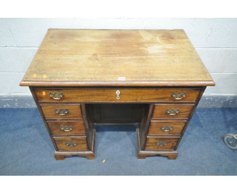 A GEORGIAN MAHOGANY KNEE HOLE DESK, with an assortment of seven drawers and a central cupboard door, width 92cm x depth 55cm 