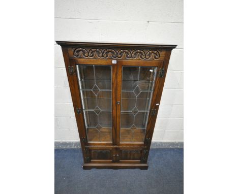 AN OLD CHARM OAK LEAD GLAZED TWO DOOR DISPLAY CABINET, with three internal shelves, and two small linenfold bottom doors, wid