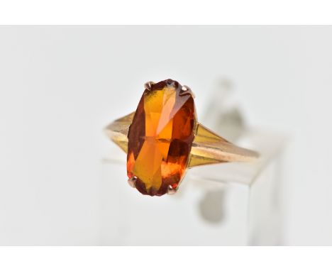 A YELLOW METAL PASTE SINGLE STONE RING, the fancy shape orange paste claw set, to the tapered shoulders and similarly designe
