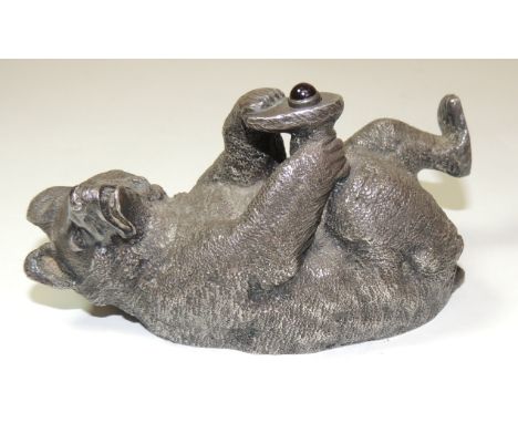 A decorative silver novelty bell push in the form of a bear lying on its back holding one of it's back feet in its front paws