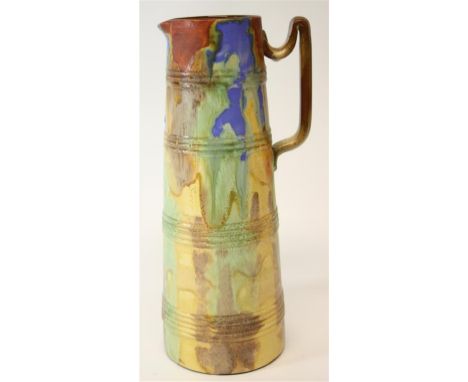 An early 20th Century Watcombe Pottery pitcher.  Of tapered form and graduated hooped bands.  With a multi-coloured running g