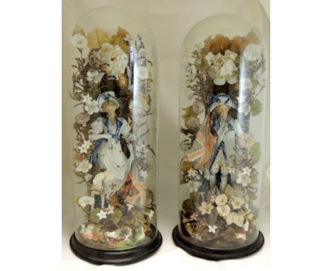 A pair of Victorian decorative arrangements under glass domes, each centred with a porcelain figure of a young woman and youn