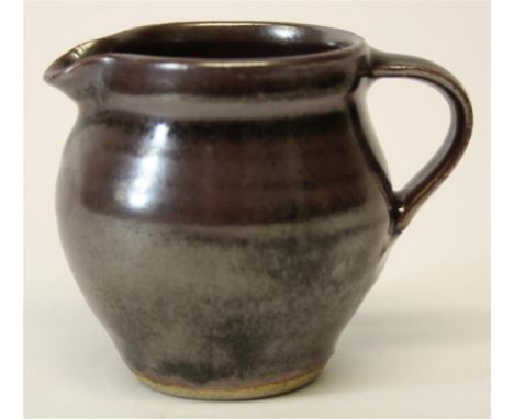 A St. Ives, Leach Studio Pottery jug; with a temoku glazed body and an impressed St. Ives seal mark below the handle.  8 cm h