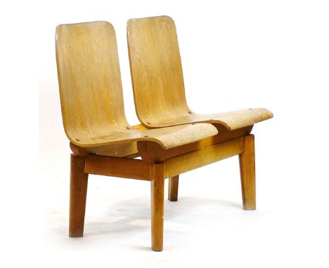 A 1960's bent ply bench with two seats on tapering block feet, moulded book racks to the rear