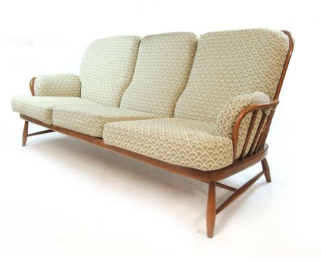 An Ercol 'golden' elm lounge suite including a three seater sofa with loose cushions and two matching armchairs