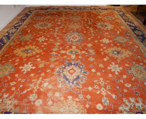 A red ground Turkish carpet, polychrome decorated with floral spandrels, amongst geometric medallions, within an indigo styli
