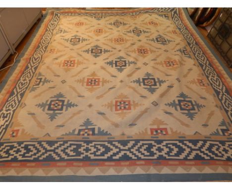 A cream ground Turkish kelim carpet, decorated with geometric medallions to centre within pale blue borders. 320 x250cm