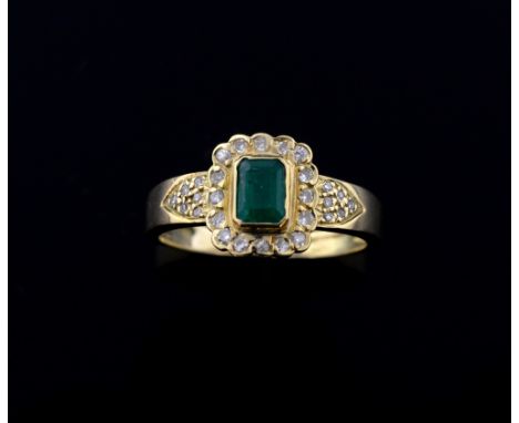 Emerald and diamond ring, the step cut emerald within a border of diamonds, and diamond set shoulders, 18 ct gold  