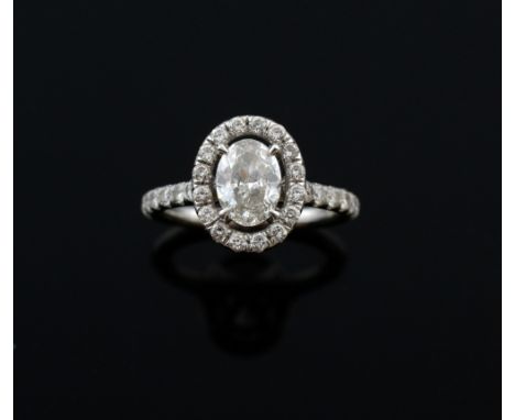  Diamond ring in halo setting, with central oval brilliant cut stone estimated at .7 carats, within a border of pave set diam