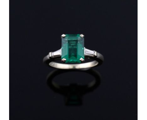 A synthetic emerald and diamond ring, Step-cut synthetic emerald to centre flanked by two baguette cut diamonds mounted in 14