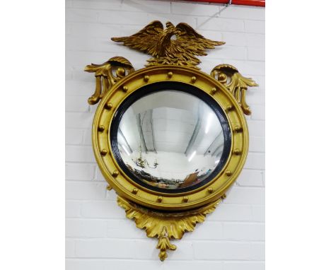 A Regency style convex wall mirror with ebonised slip and gilt ball and eagle surmount