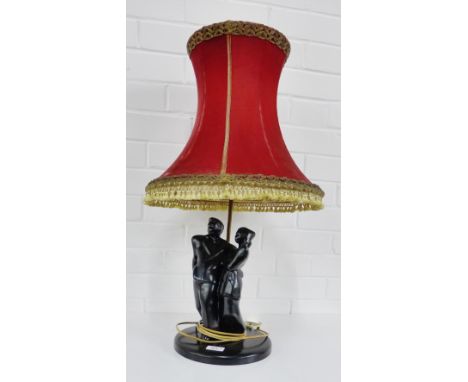 A matt black glazed figural table lamp base complete with a red velvet shade