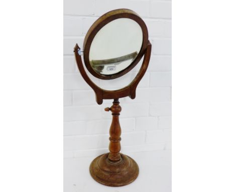 A mahogany framed oval mirror on a baluster column and circular base, 70cm high